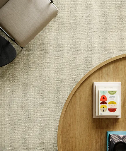 Beige 100% Wool Carpet in Modern Living Room Setting Overhead view of a modern living room with a beige 100% wool carpet, a beige chair, and a wooden coffee table with books