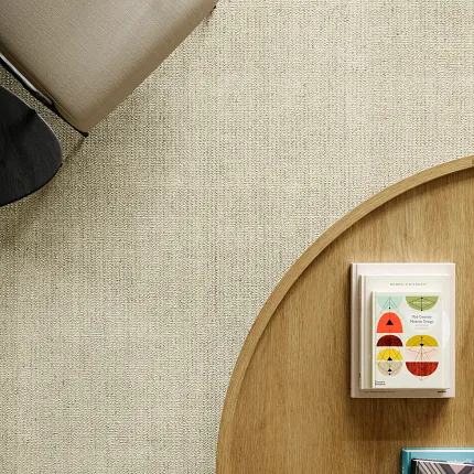 Beige 100% Wool Carpet in Modern Living Room Setting Overhead view of a modern living room with a beige 100% wool carpet, a beige chair, and a wooden coffee table with books