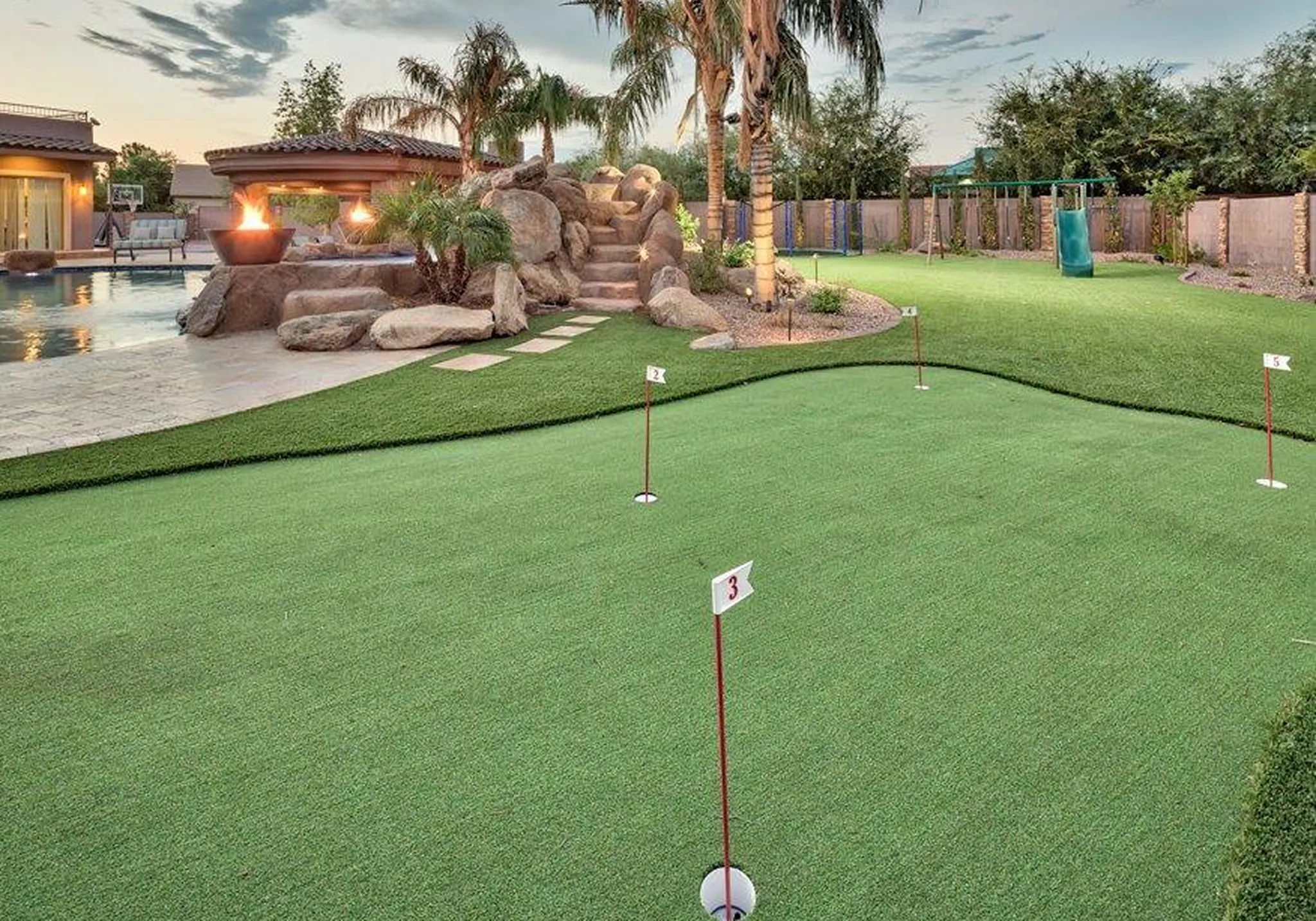 Backyard putting green with artificial turf and landscaping