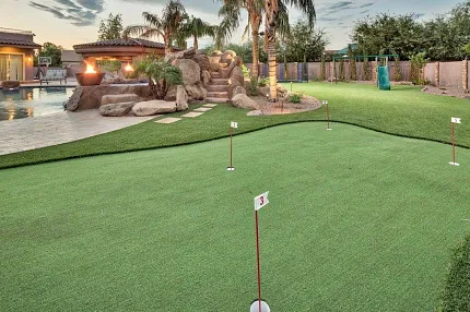 Enhance your outdoor space with a realistic putting green Backyard putting green with artificial turf and landscaping