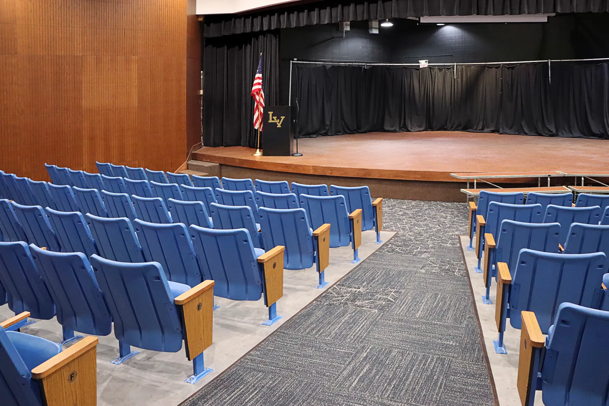 Auditorium with blue seating and carpet flooring in an education facility