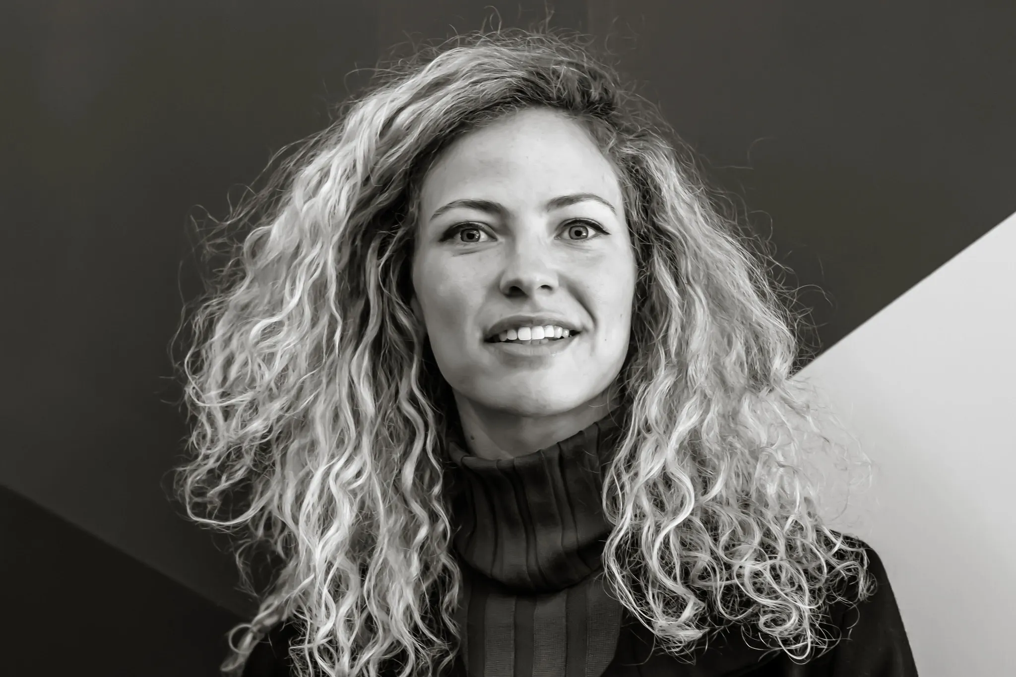 Black and white image of a person with curly hair against a geometric background