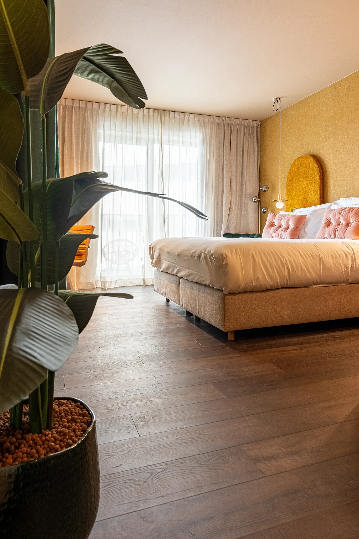 Colourful bedroom with warm yellow wall and warm wooden Coretec floor