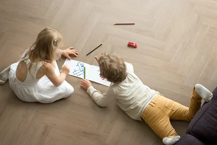 Light Wood Look Luxury Vinyl Plank Flooring in Living Room Scene Children drawing on light wood look luxury vinyl plank flooring in a living room setting