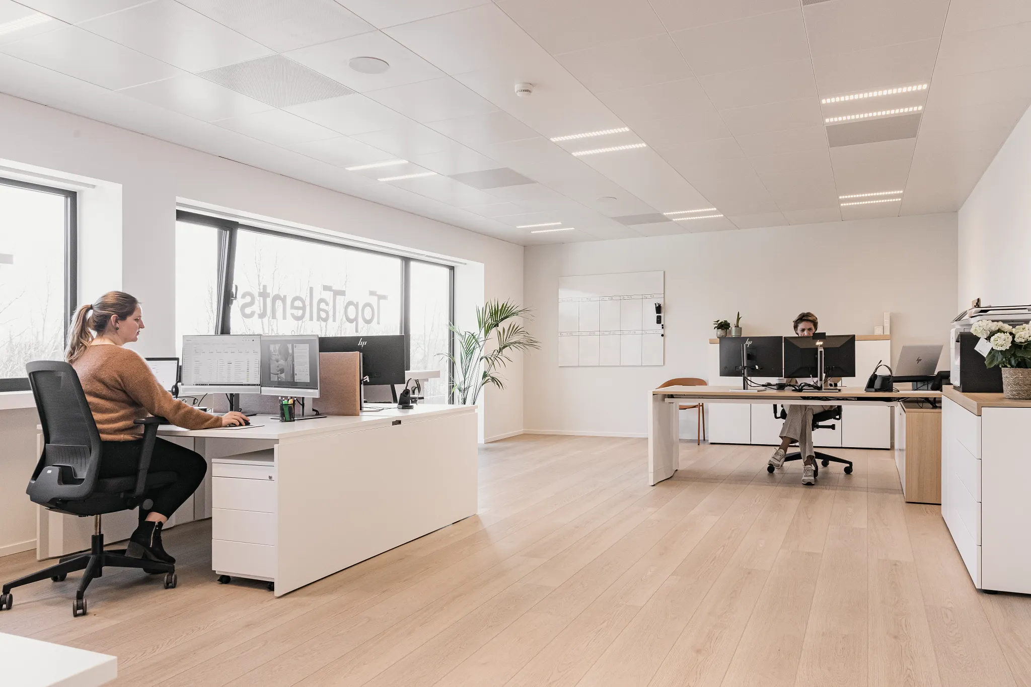 Open office floor plan with view outside and rich wood herringbone floor from Coretec 