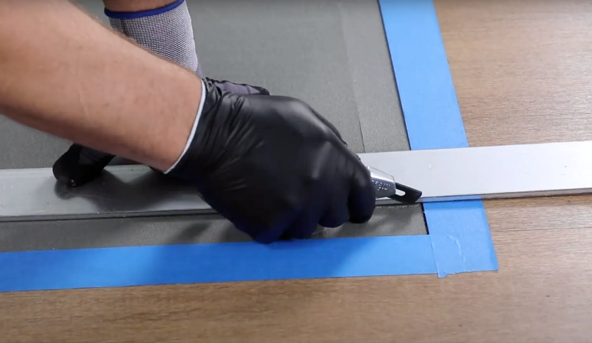 Person installing flooring with a utility knife and measuring tool