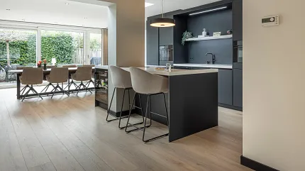 Licht eiken laminaatvloer voor een gezellige eetkamer sfeer Moderne eetkamer met licht eiken laminaatvloeren en bruine stoelen