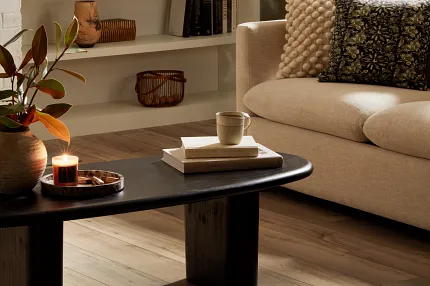 SPC Flooring in Natural Wood Tones for a Cozy Living Room - 48.03x7.08 inch Cozy living room with beige sofa, decorative pillows, and a black coffee table on SPC flooring in natural wood tones