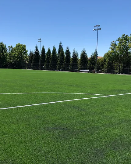 Outdoor field with artificial grass and clear sky Expansive outdoor field with lush green artificial turf under a clear blue sky