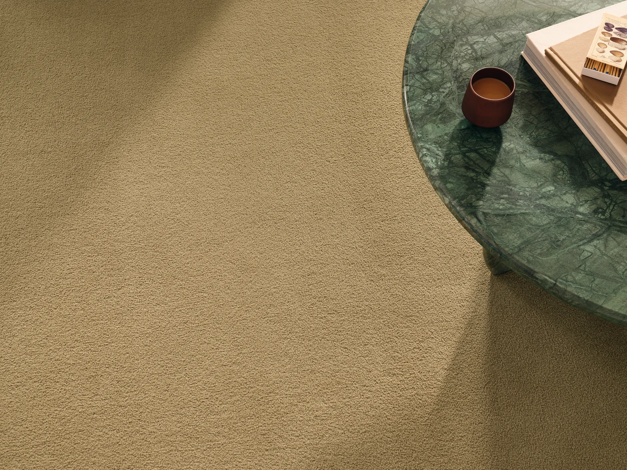 Beige synthetic carpet with a green marble table and books