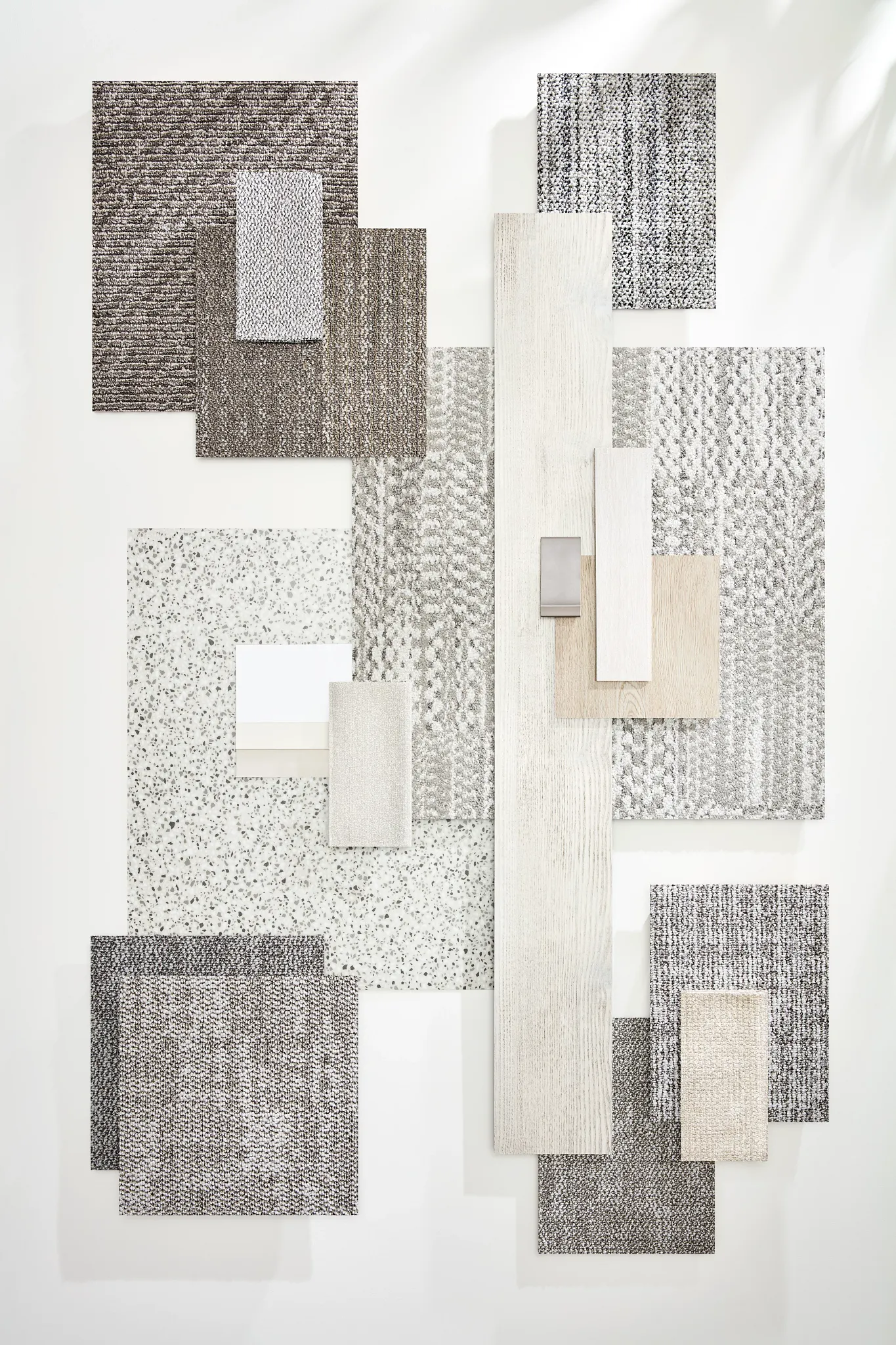 Assorted carpet and hard surface flooring samples in neutral tones