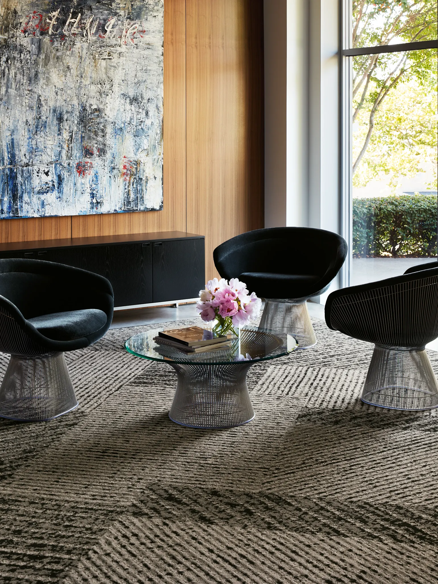 Modern office lounge with abstract art and plush black chairs on patterned commercial carpet tile