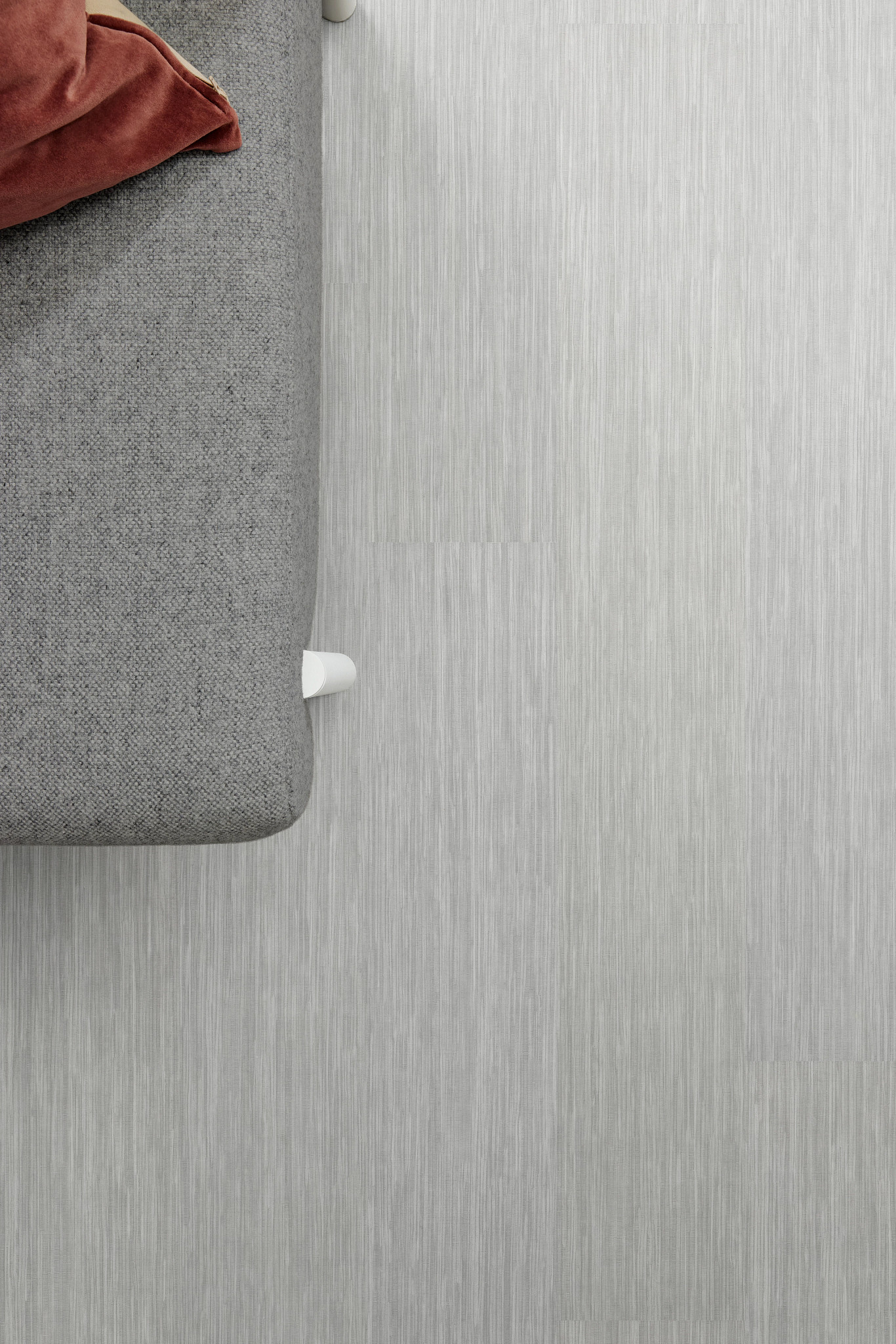 Grey flooring with subtle linear texture next to a grey upholstered sofa and a red cushion, 48x7.75 inch dimensions