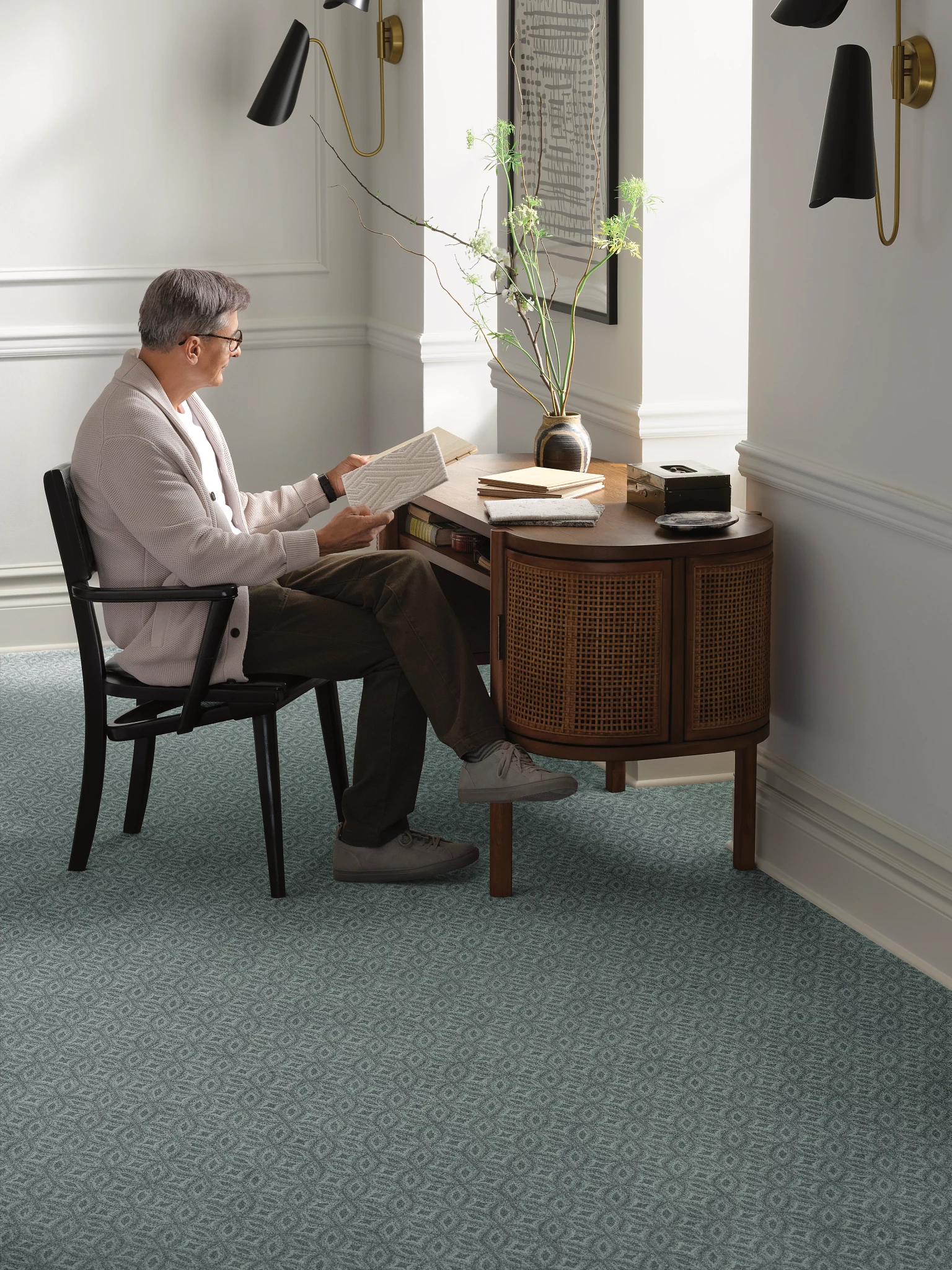 Elderly man reading in a room with teal geometric pattern broadloom carpet flooring