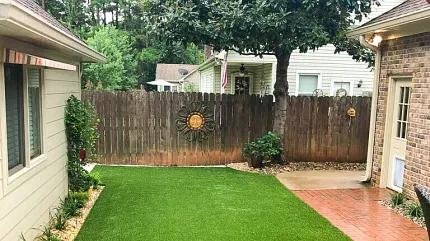 Small Backyard Artificial Turf Installation | Low-Maintenance Lawn Compact residential backyard with freshly installed artificial turf lawn bordered by brick patio and wooden privacy fence.