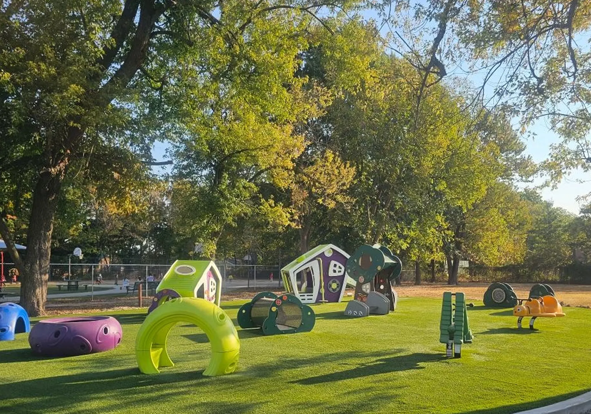 Colorful playground equipment on green grass under trees
