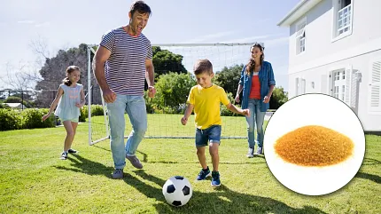 Outdoor fun with durable lawn infill for sports activities Family playing soccer on grass lawn with close-up of infill material