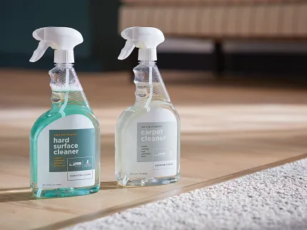 Kid and Pet-Friendly Floor Cleaners for Laminate and Carpet Floors Two bottles of kid and pet-friendly floor cleaners on a light wood laminate floor next to a beige carpet