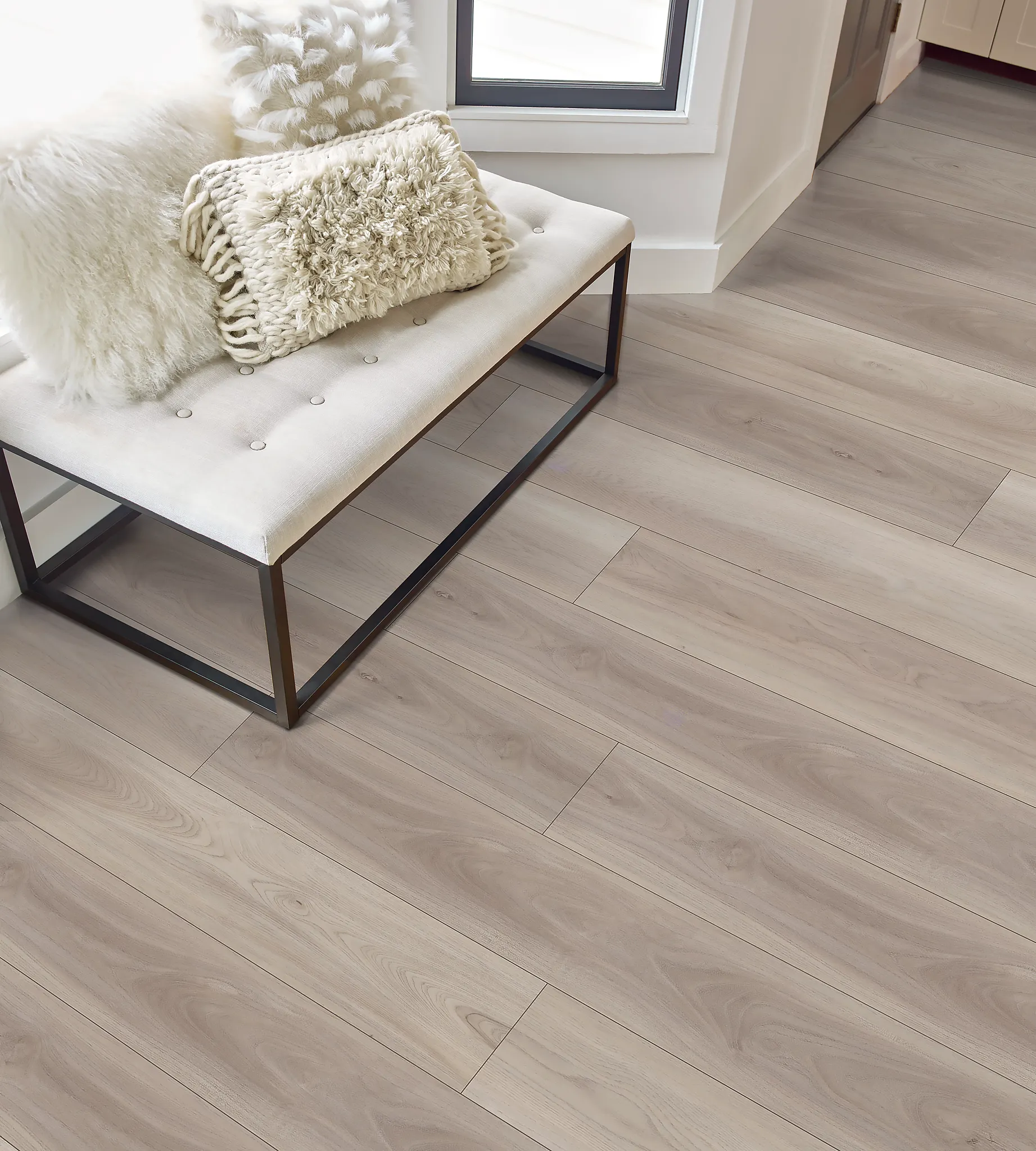 Modern living room with light wood flooring and a cozy bench with plush pillows