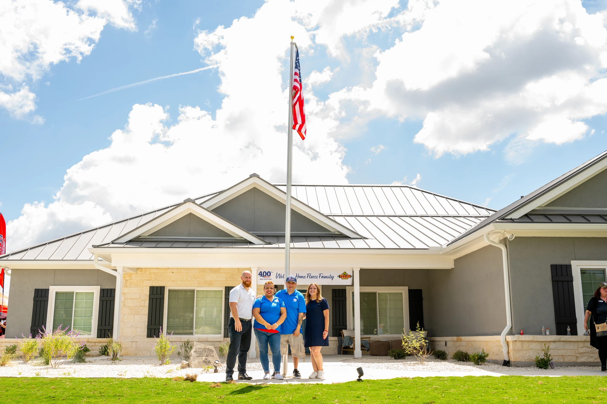 Group of people standing in front of a modern residential building with an American flag