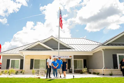 Modern Residential Building with American Flag and Group of People Group of people standing in front of a modern residential building with an American flag