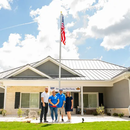 Modern Residential Building with American Flag and Group of People Group of people standing in front of a modern residential building with an American flag