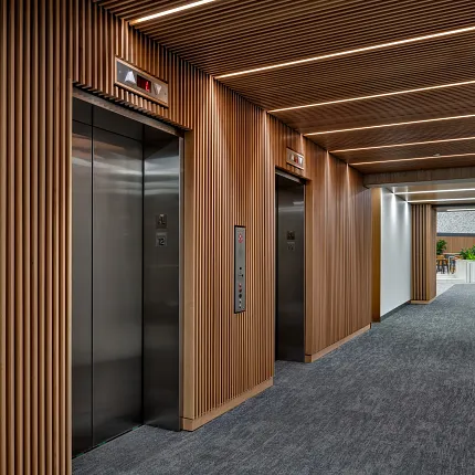 Workplace Entryway with Commercial Carpet Tile Flooring and Wooden Paneling. Modern workplace entryway with 24x24 inch commercial carpet tile flooring, featuring sleek elevators and wooden paneling.