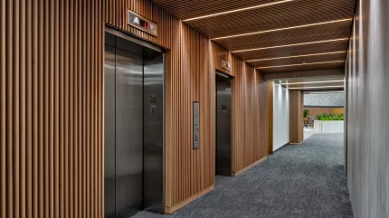 Workplace Entryway with Commercial Carpet Tile Flooring and Wooden Paneling. Modern workplace entryway with 24x24 inch commercial carpet tile flooring, featuring sleek elevators and wooden paneling.