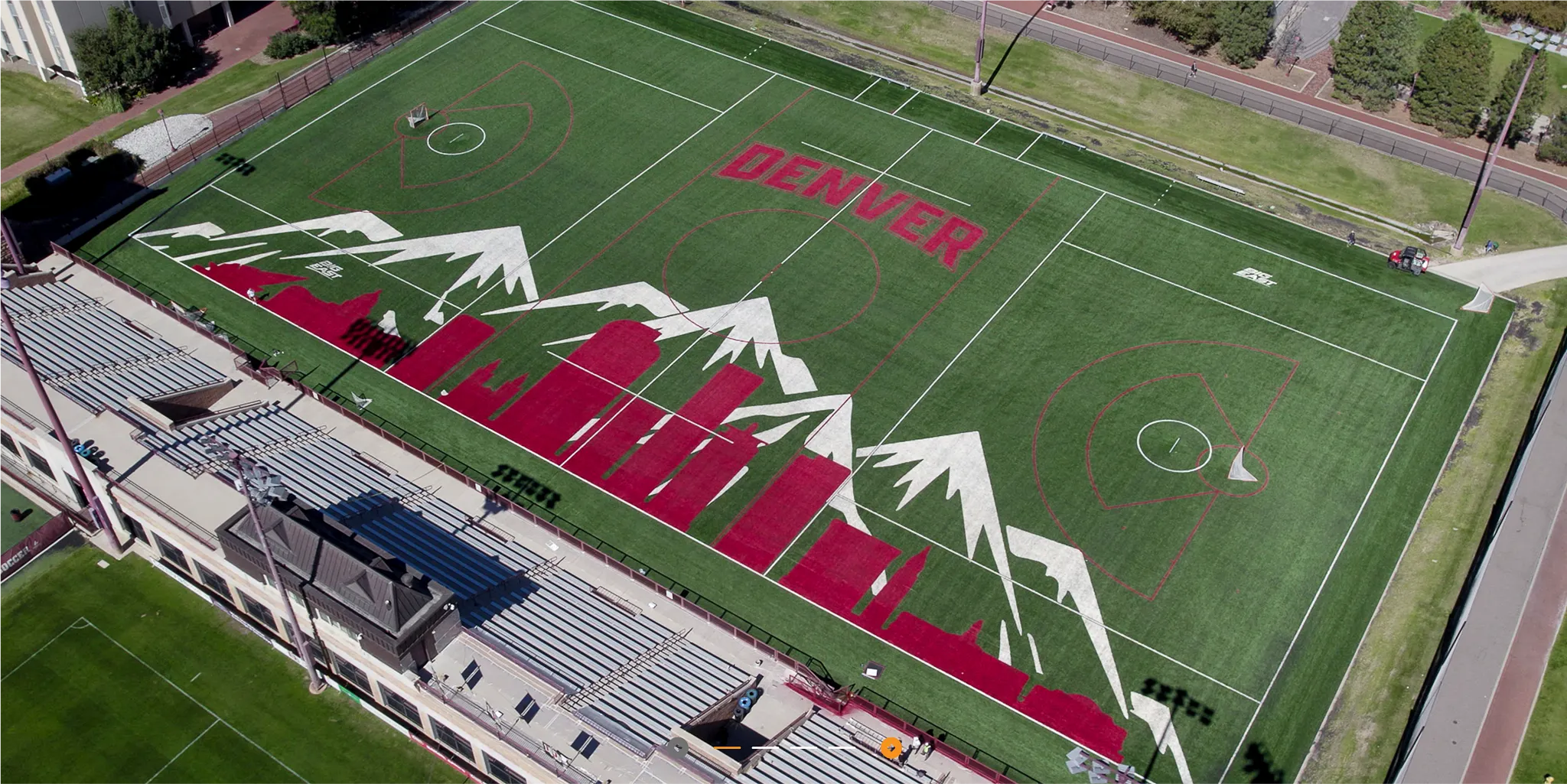 Aerial view of a sports field with artificial turf featuring Denver skyline and mountain design in red and white