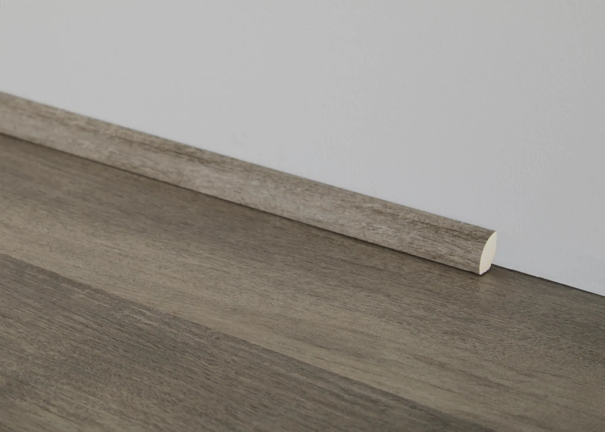 Close-up of gray wood-look flooring with matching quarter round molding