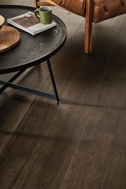 Premium Dark Brown Hardwood Flooring for Elegant Interiors Dark brown hardwood flooring in a living room with a black round table and a leather sofa