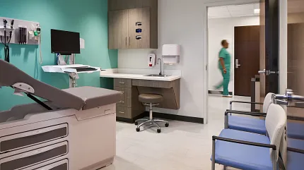 Healthcare Facility Examination Room with Light Flooring and Teal Accent Wall Modern healthcare facility examination room with teal accent wall, medical equipment, and light-colored flooring