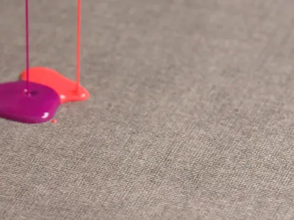 Gray Commercial Carpet Tile with Liquid Spills Close-up of gray commercial carpet tile with pink and purple liquid spills