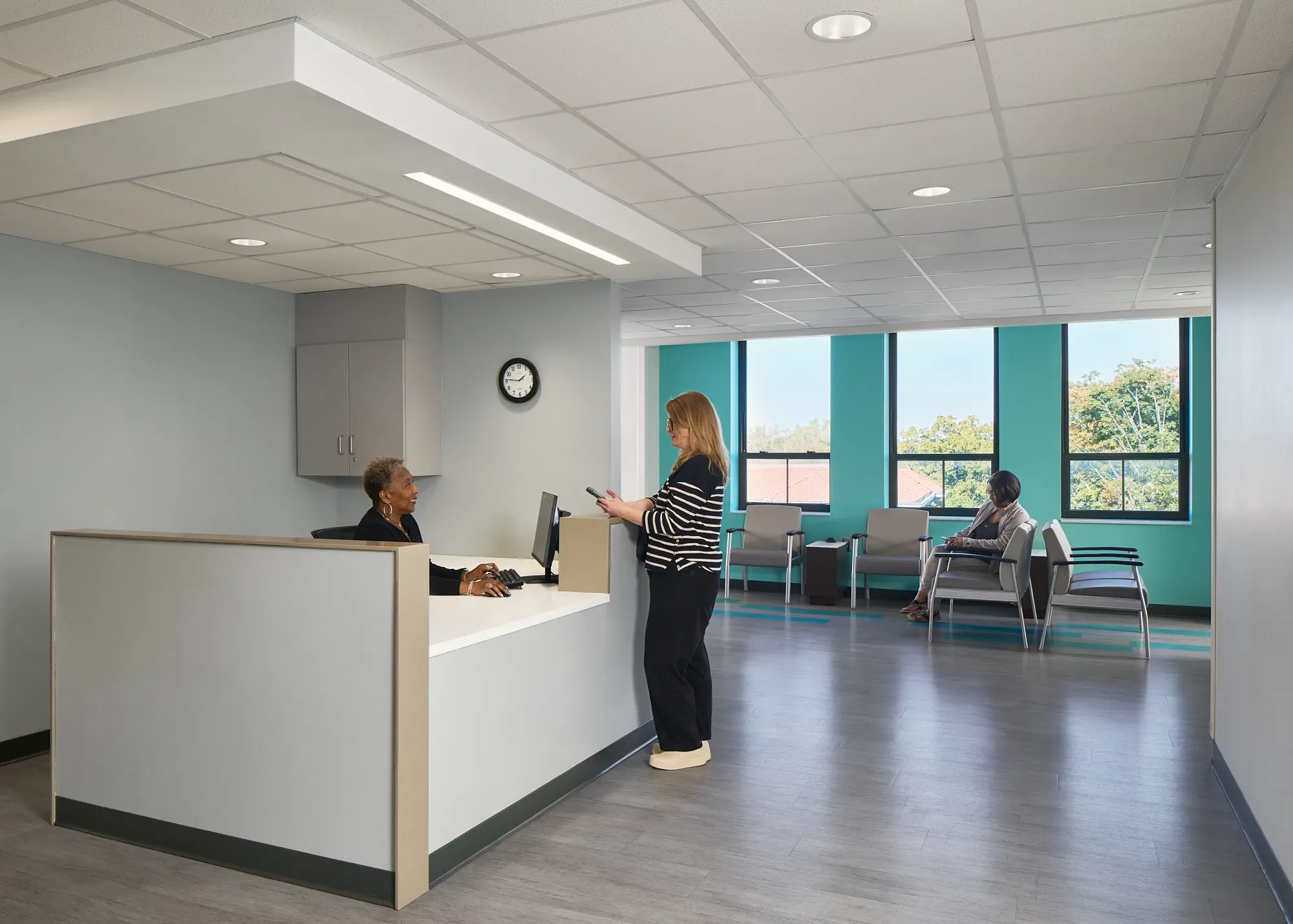 Healthcare facility reception area with modern flooring and two people interacting at the desk