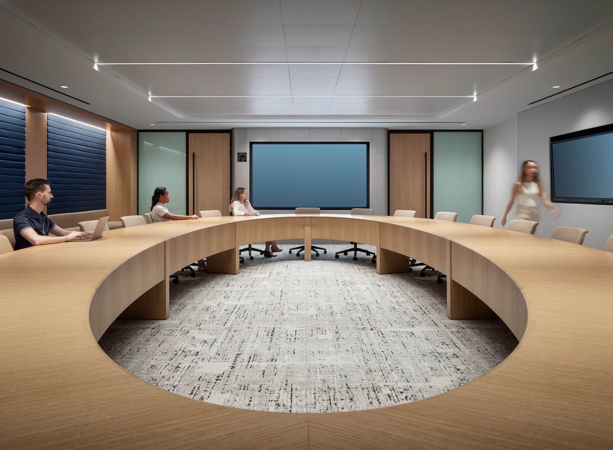 Modern workplace conference room with circular wooden table and commercial carpet tile flooring