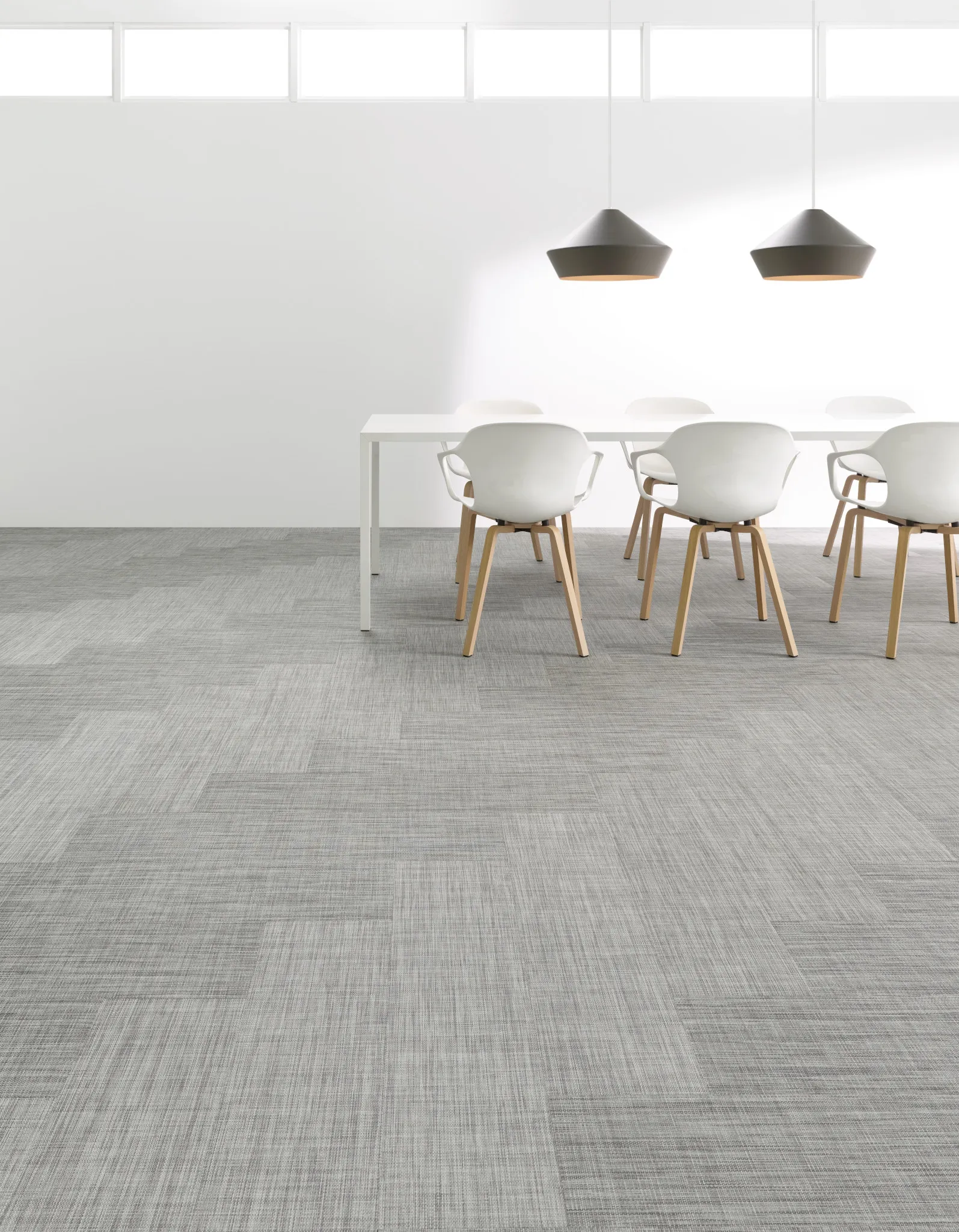 Modern commercial carpet tile in shades of gray, blue, red, yellow, and green with a black bench and books in an education facility setting