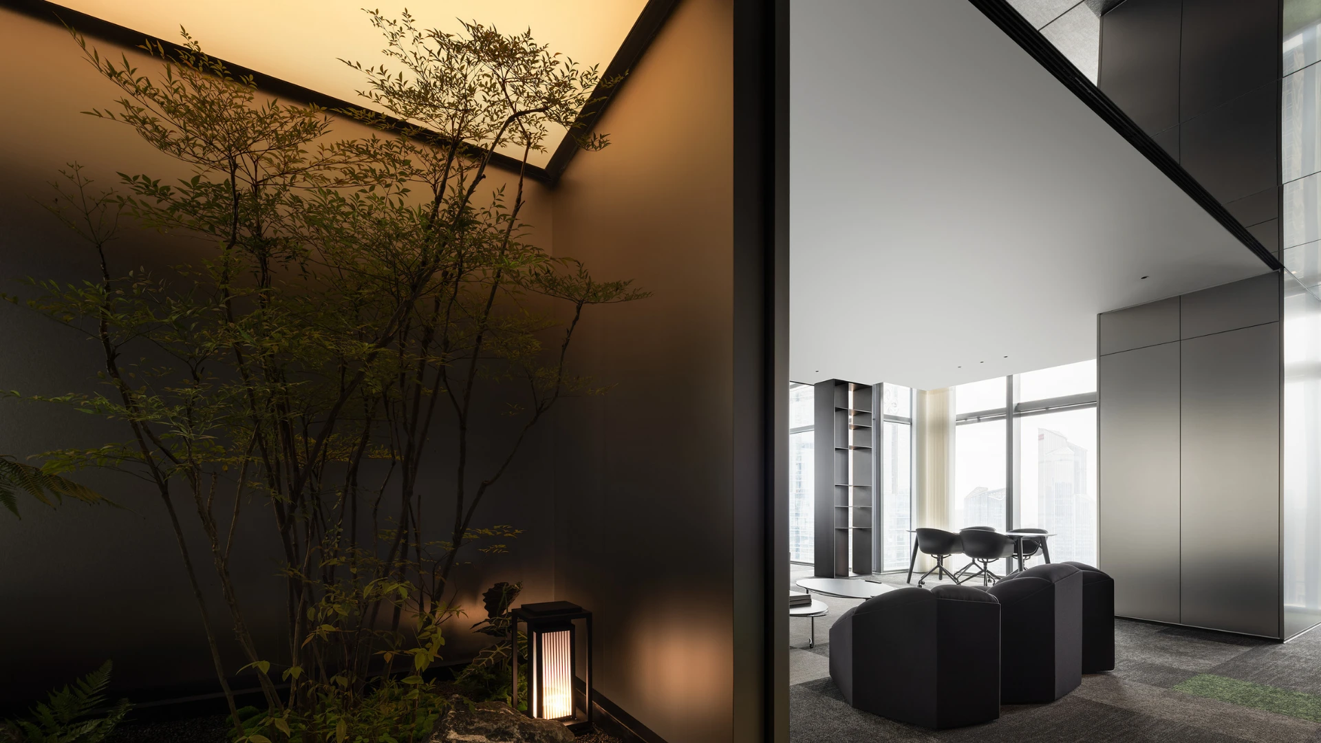 Modern office interior with black furniture and large windows, featuring a serene indoor garden with ambient lighting