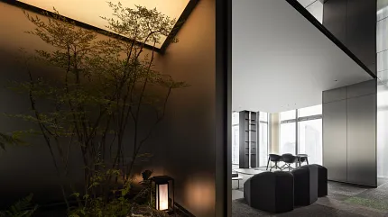Contemporary office space with indoor garden and stylish black seating. Modern office interior with black furniture and large windows, featuring a serene indoor garden with ambient lighting