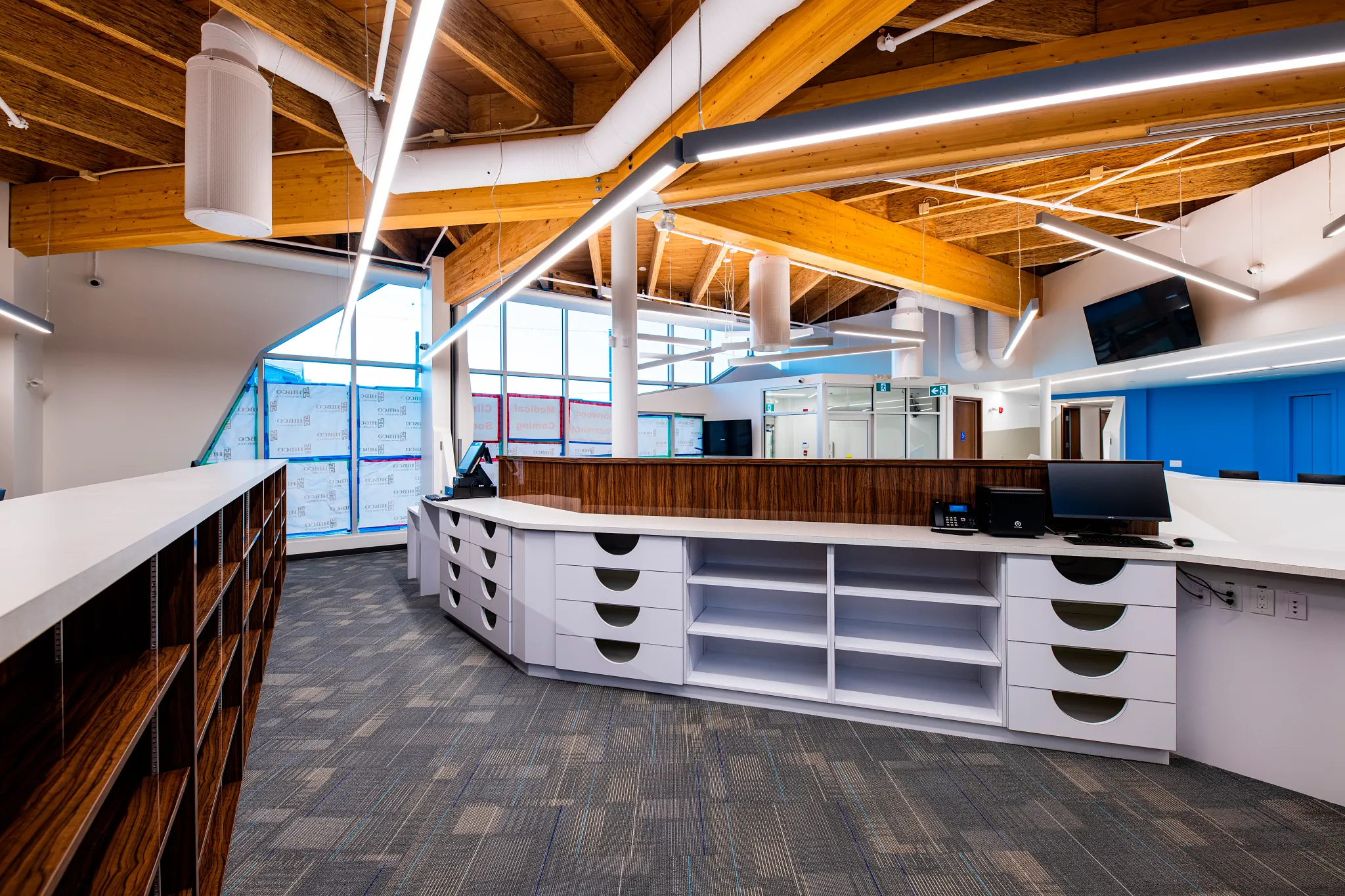 Modern retail facility with commercial carpet tile flooring, featuring a spacious reception area with wooden ceiling beams and contemporary lighting.