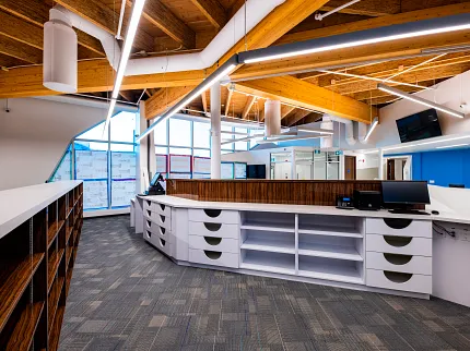 Retail Facility with Commercial Carpet Tile Flooring and Modern Interior Design Modern retail facility with commercial carpet tile flooring, featuring a spacious reception area with wooden ceiling beams and contemporary lighting.