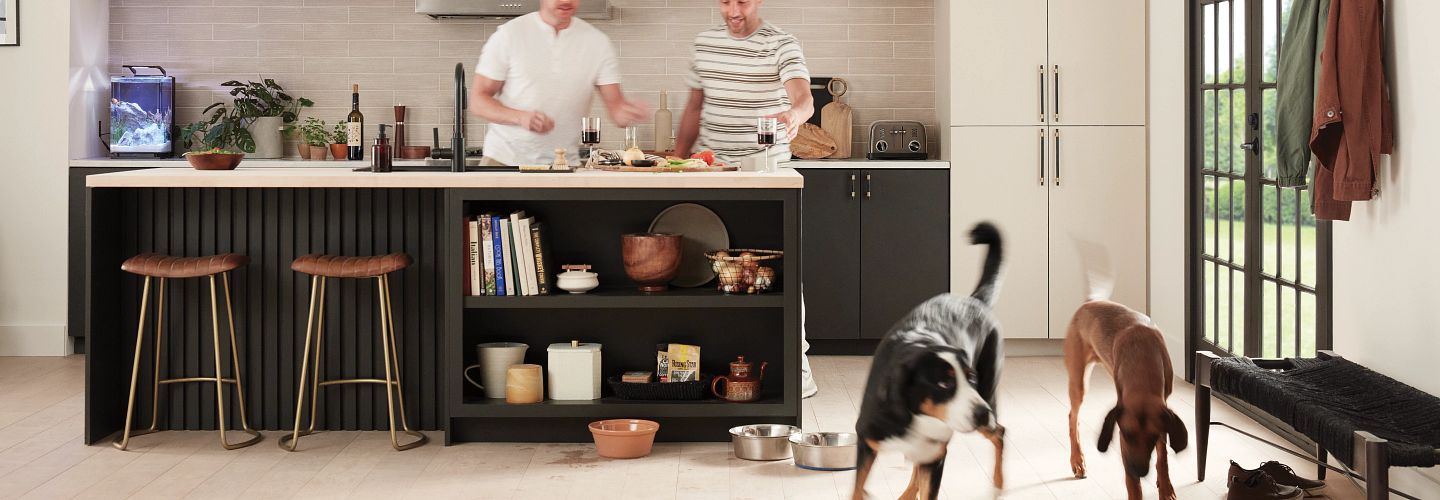 family preparing dinner at kitchen island and two large gogs running across the floor