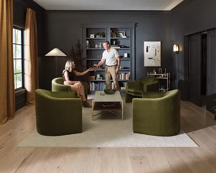 Elegant Living Room with Durable Hardwood Flooring and Stylish Decor Cozy living room with light hardwood flooring, green armchairs, and a beige rug