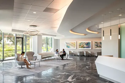 Healthcare Facility Lobby with Dark Marble Flooring and Modern Design Modern healthcare facility lobby with sleek white reception desk, contemporary seating, and large windows showcasing a view of greenery, featuring elegant dark marble flooring.