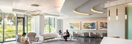 Healthcare Facility Lobby with Dark Marble Flooring and Modern Design Modern healthcare facility lobby with sleek white reception desk, contemporary seating, and large windows showcasing a view of greenery, featuring elegant dark marble flooring.