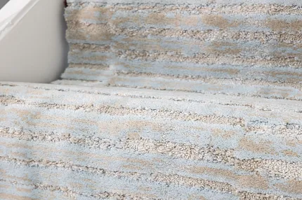Textured Light Blue and Beige Carpet on Stairs Close-up of carpeted stairs featuring a textured pattern in light blue and beige colors