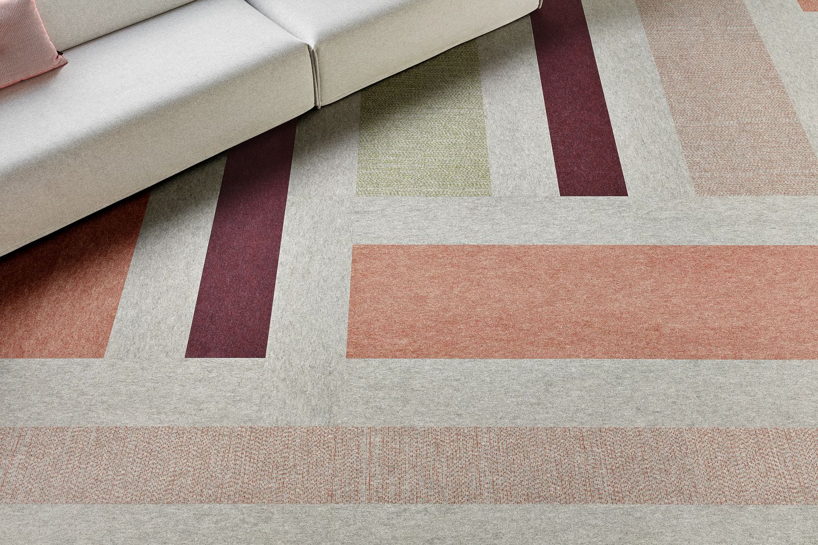 Geometric Pattern Commercial Carpet Tile in Grey, Orange, Burgundy, and Green with Sofa Modern commercial carpet tile in shades of grey, orange, burgundy, and green with a geometric pattern, featuring a light grey sofa with a pink cushion