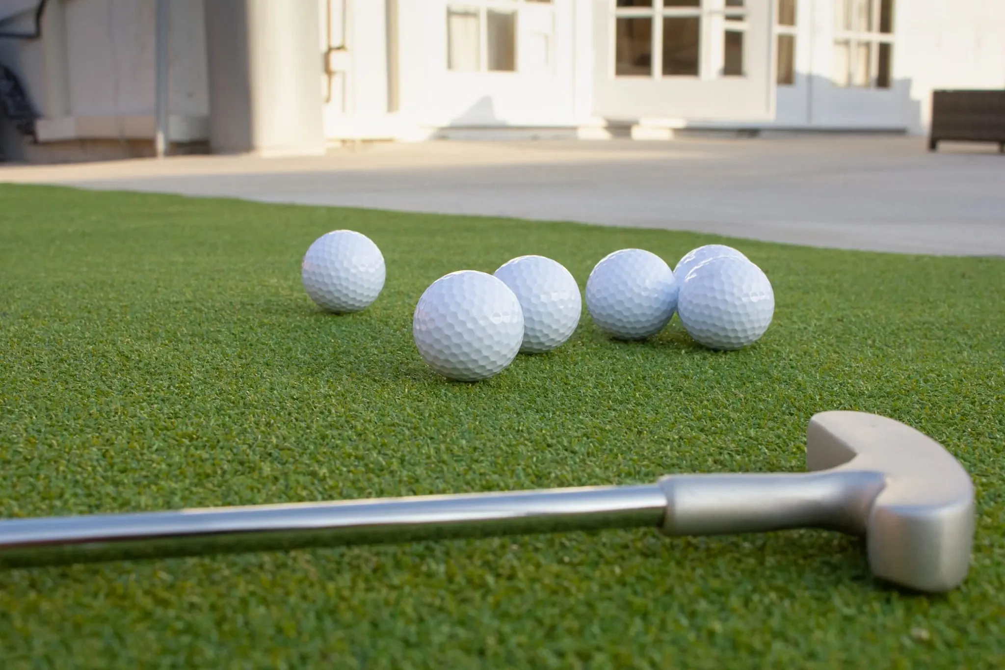 Golf balls and putter on artificial grass