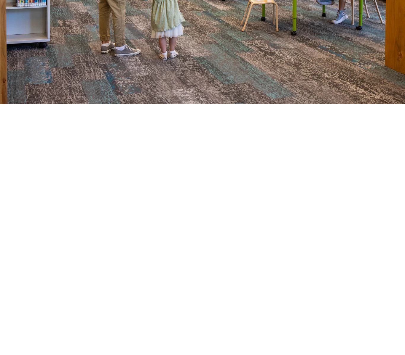 A woman looking at what a child is pointing to up in the sky, looking at the hanging fixtures in the library