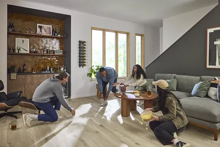 Light Wood Look Luxury Vinyl Plank Flooring in Modern Living Room Scene Modern living room with light wood look luxury vinyl plank flooring and a group of young adults enjoying a casual gathering