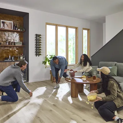 Light Wood Look Luxury Vinyl Plank Flooring in Modern Living Room Scene Modern living room with light wood look luxury vinyl plank flooring and a group of young adults enjoying a casual gathering